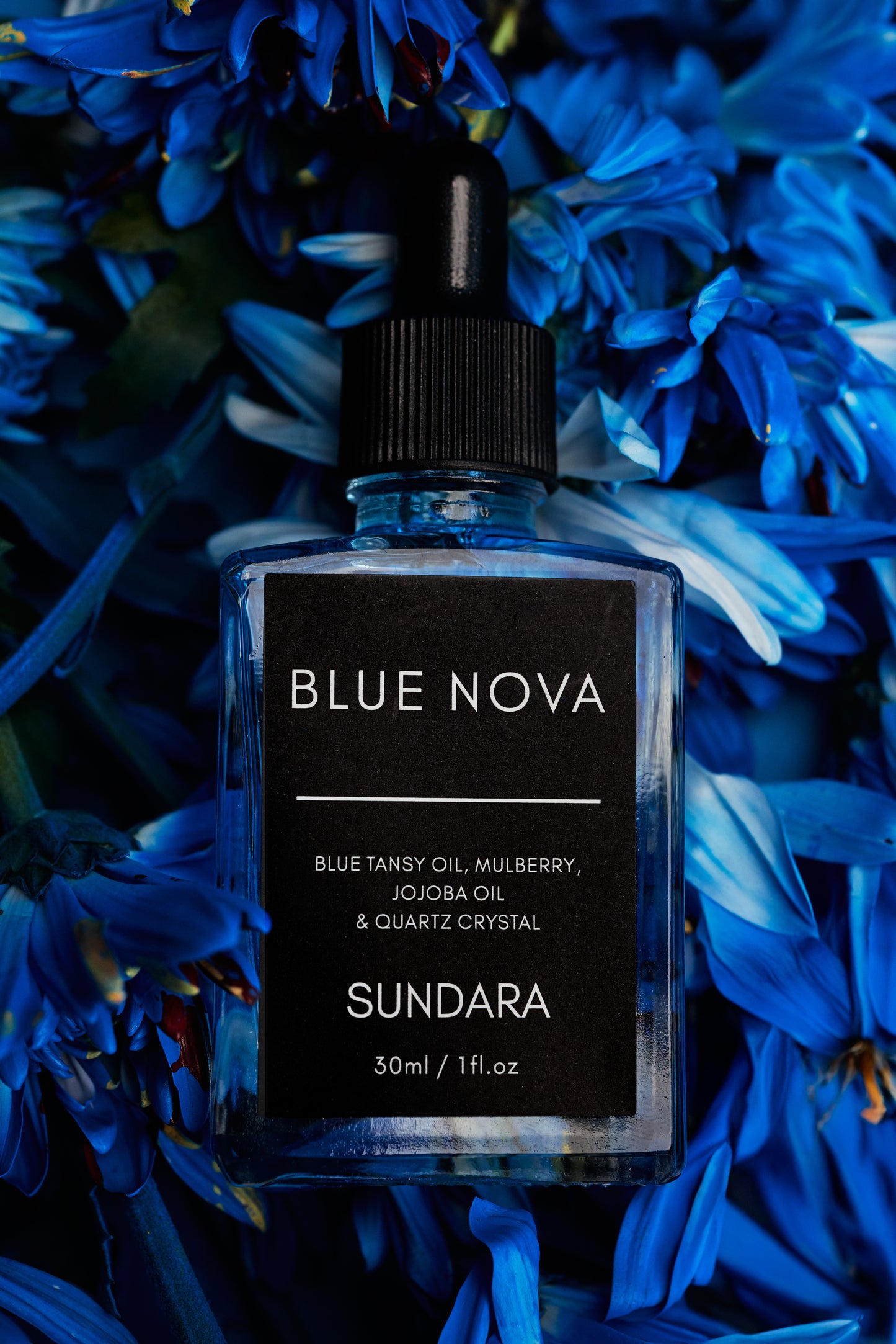 Sundara Blue Nova oil bottle on a bed of blue flowers