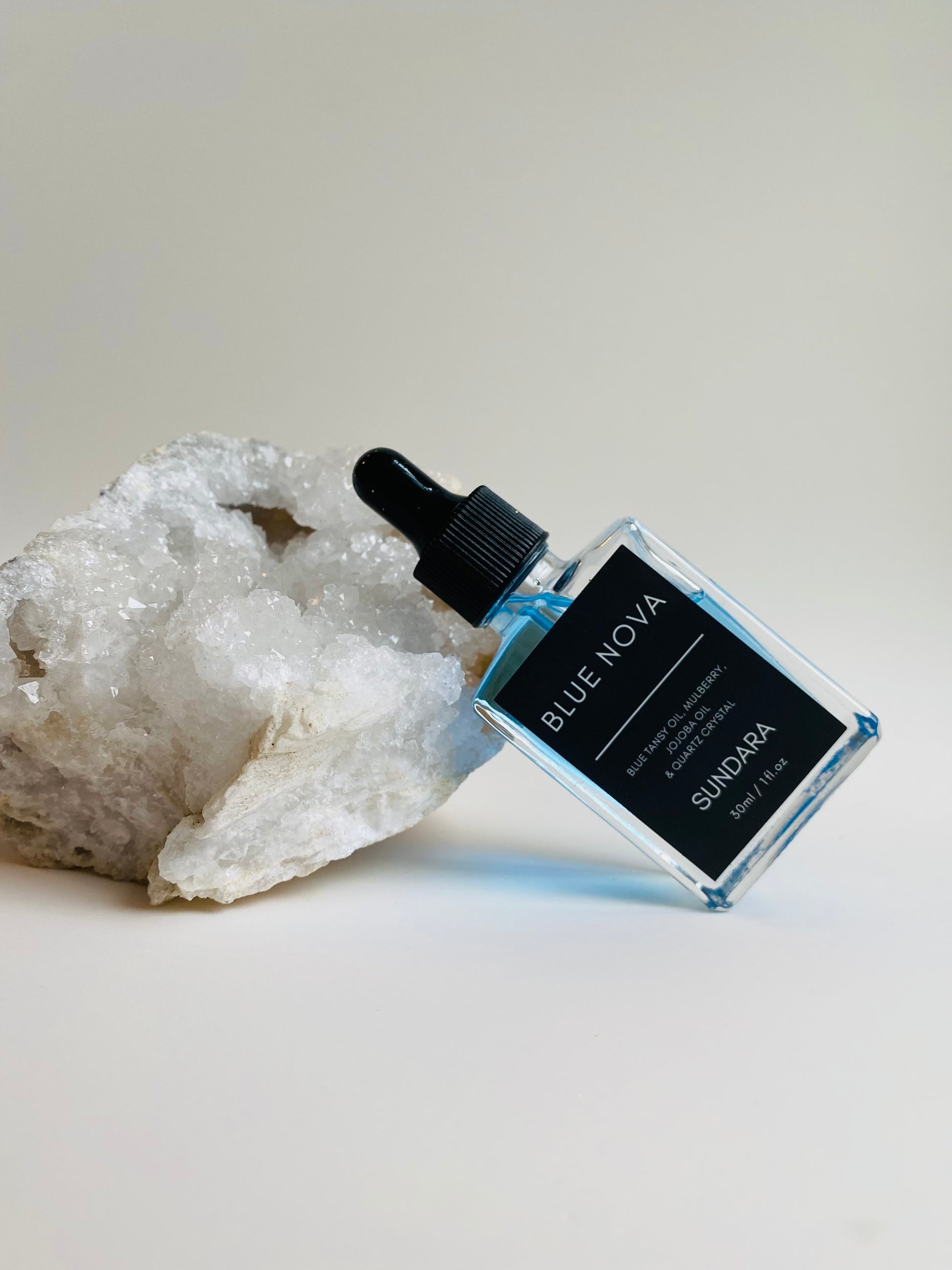 Soul of Sundara Blue Nova oil balancing on quartz crystal. Blue tansy oil, mulberry, jojoba oil, and quartz crystal soothing skincare