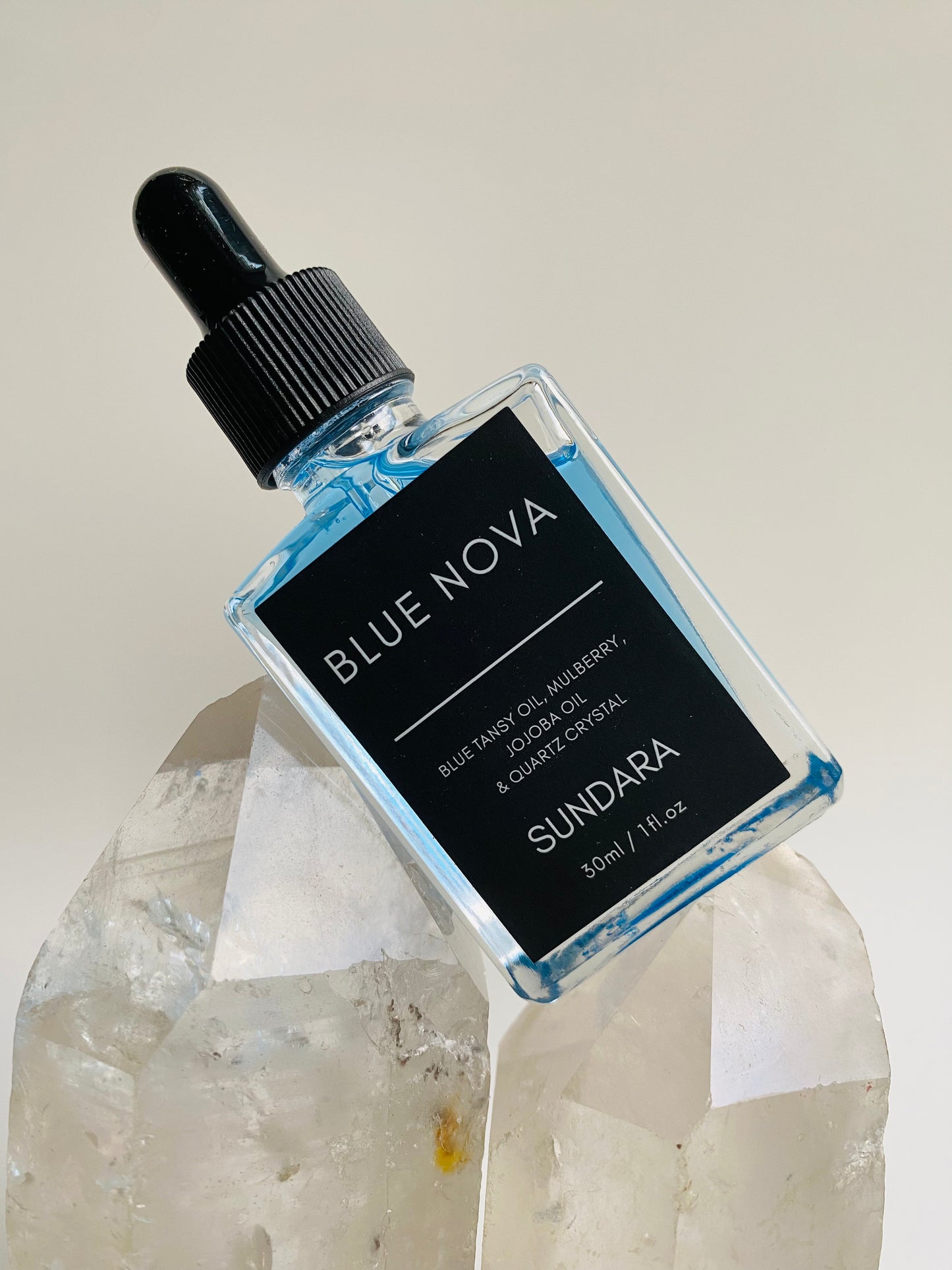 Soul of Sundara Blue Nova oil balancing on quartz crystal. Blue tansy oil, mulberry, jojoba oil, and quartz crystal soothing skincare