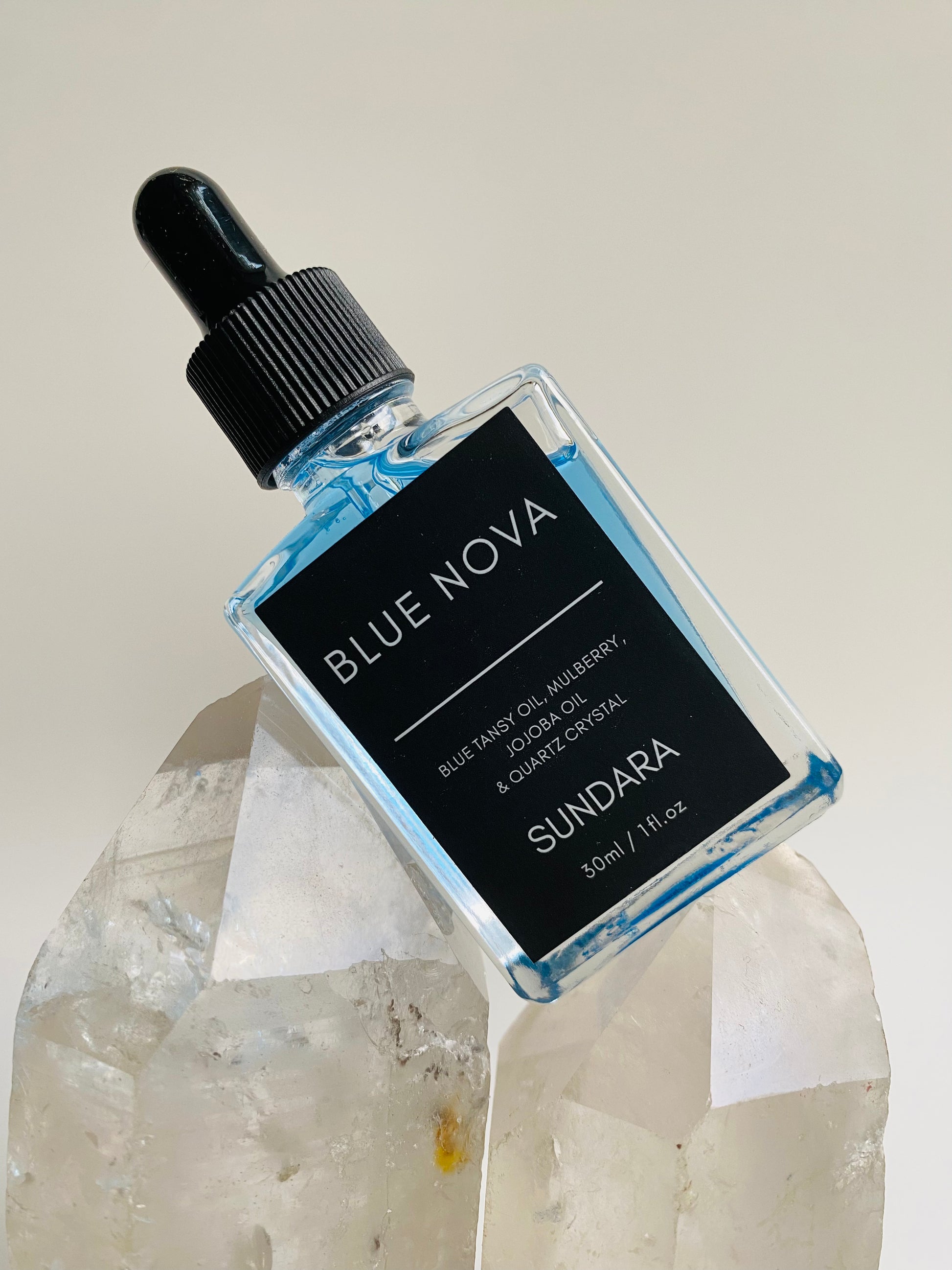 Soul of Sundara Blue Nova oil balancing on quartz crystal. Blue tansy oil, mulberry, jojoba oil, and quartz crystal soothing skincare