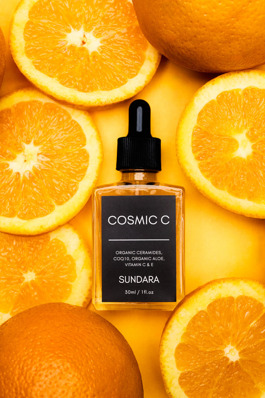 Cosmic C Sundara skincare serum bottle surrounded by oranges on a yellow background