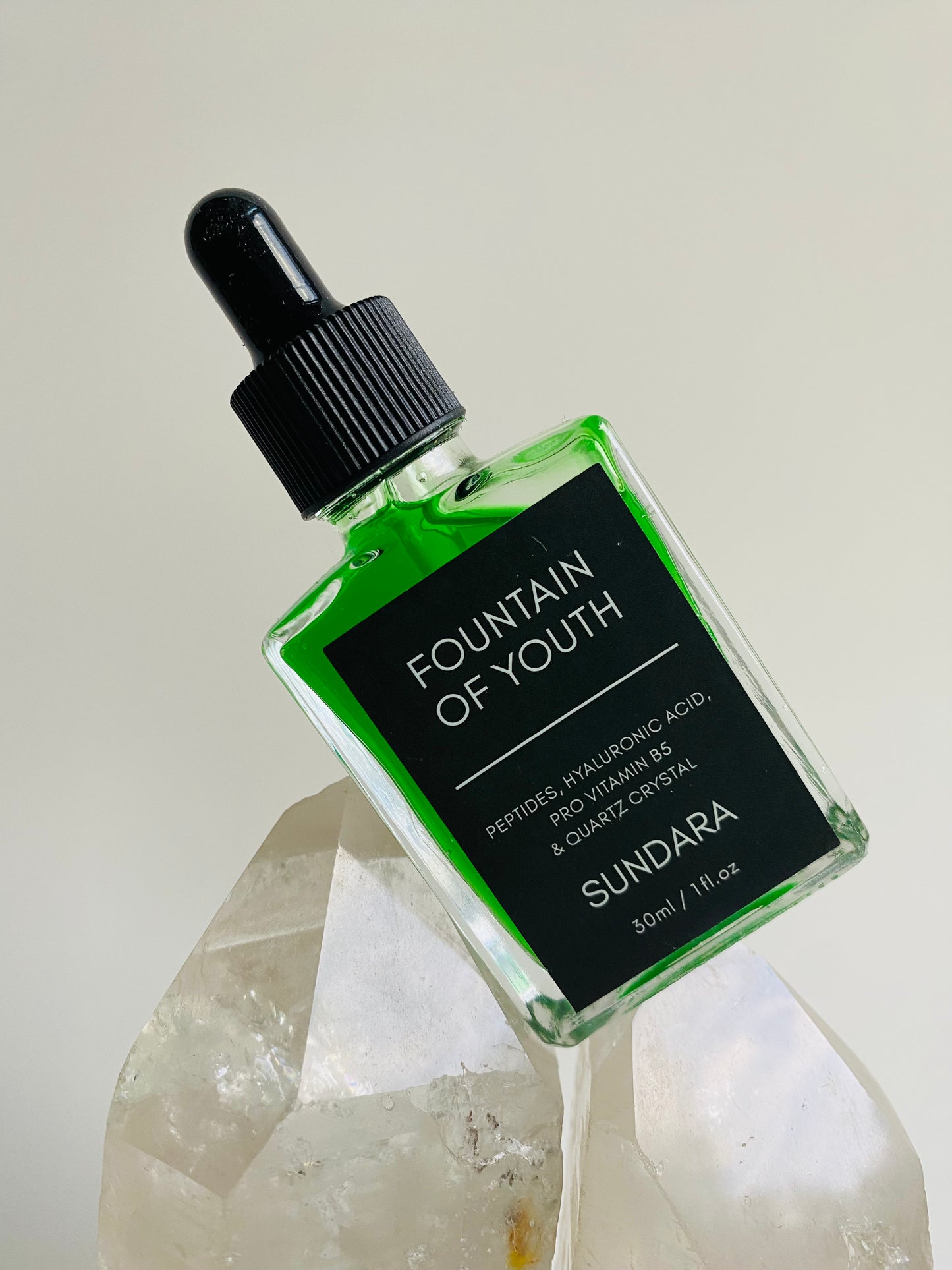 Soul of Sundara Fountain of Youth Serum propped on quartz crystal. Peptides, hyaluronic acid, quartz crystal for aging skin