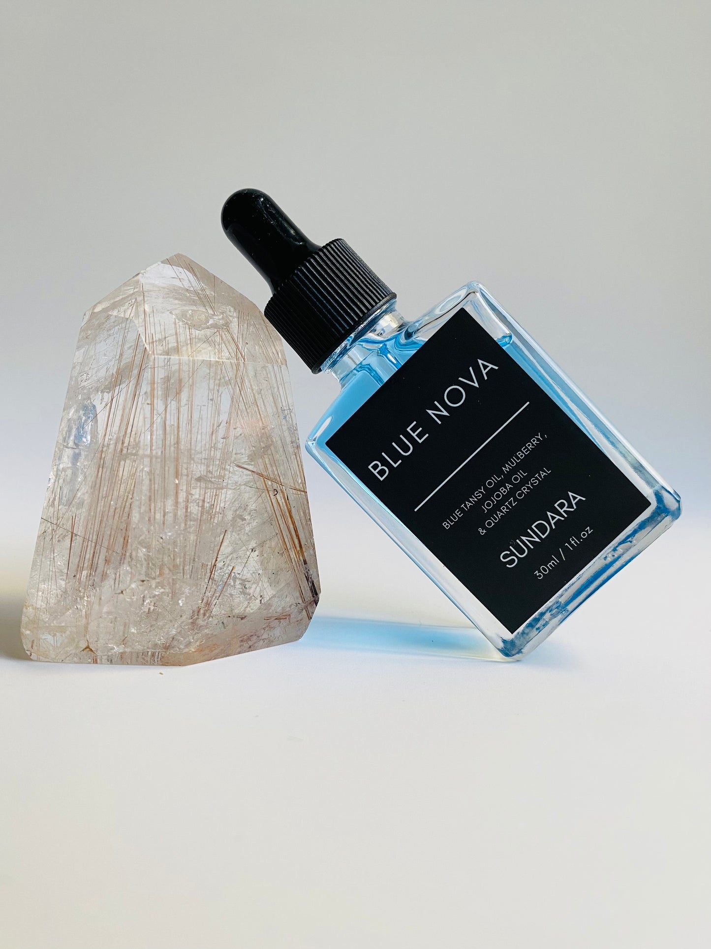 Soul of Sundara Blue Nova oil balancing on quartz crystal. Blue tansy oil, mulberry, jojoba oil, and quartz crystal soothing skincare