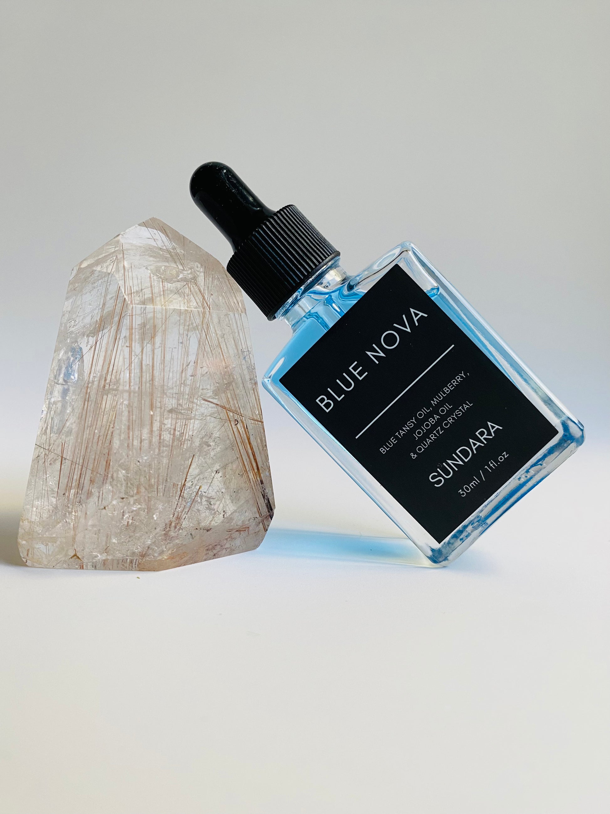 Soul of Sundara Blue Nova oil balancing on quartz crystal. Blue tansy oil, mulberry, jojoba oil, and quartz crystal soothing skincare